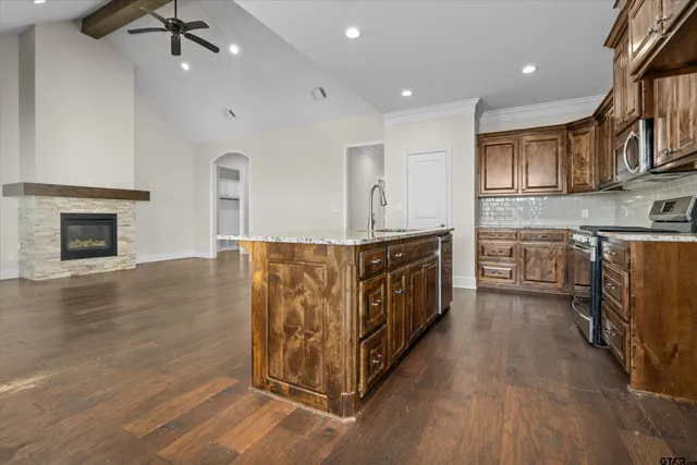 a kitchen with stainless steel appliances granite countertop a stove top oven a sink dishwasher and a oven with wooden floor