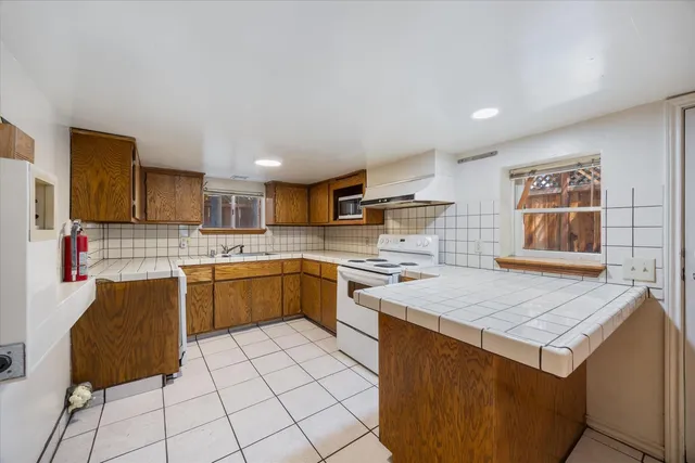 a large kitchen with stainless steel appliances kitchen island granite countertop a refrigerator and a stove top oven