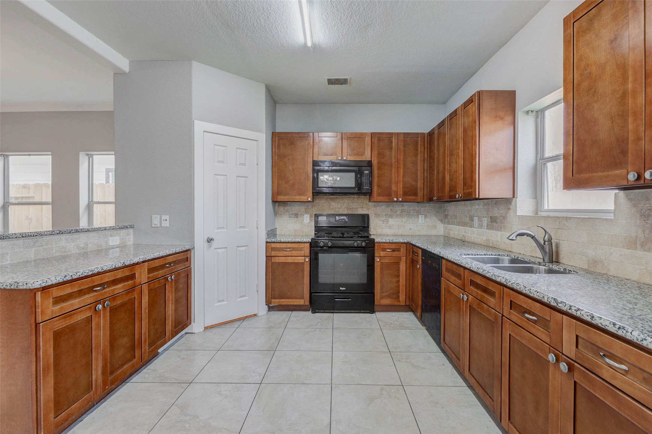 4834 Hollow Hook Road, Unit A Houston, TX 77041 - Photo 7 of 30 a kitchen with stainless steel appliances granite countertop wooden cabinets a sink and dishwasher a stove top oven with wooden floor