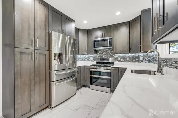 a kitchen with stainless steel appliances granite countertop a refrigerator and a stove top oven