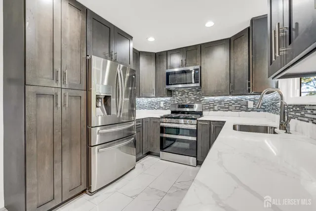 a kitchen with stainless steel appliances granite countertop a refrigerator and a stove top oven