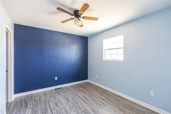 an empty room with wooden floor fan and windows