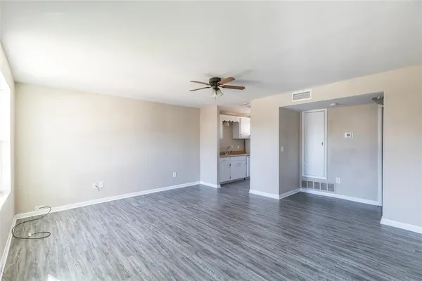 a view of an empty room with a window and wooden floor