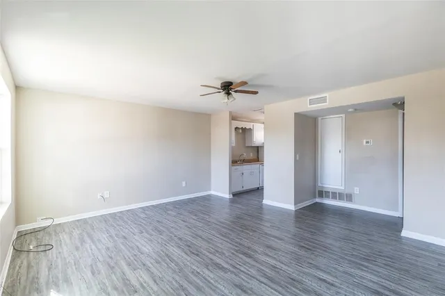 a view of an empty room with a window and wooden floor