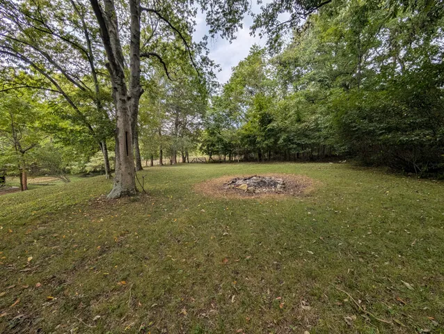 a view of a house with a yard and large trees