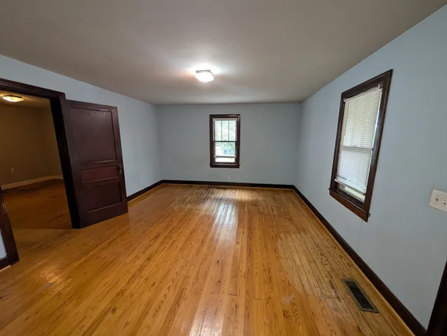 an empty room with wooden floor and mirror
