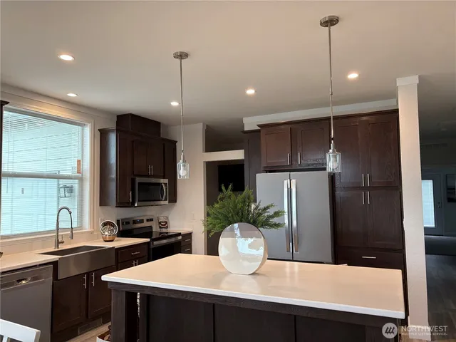 a kitchen with a refrigerator a sink cabinets and wooden floor
