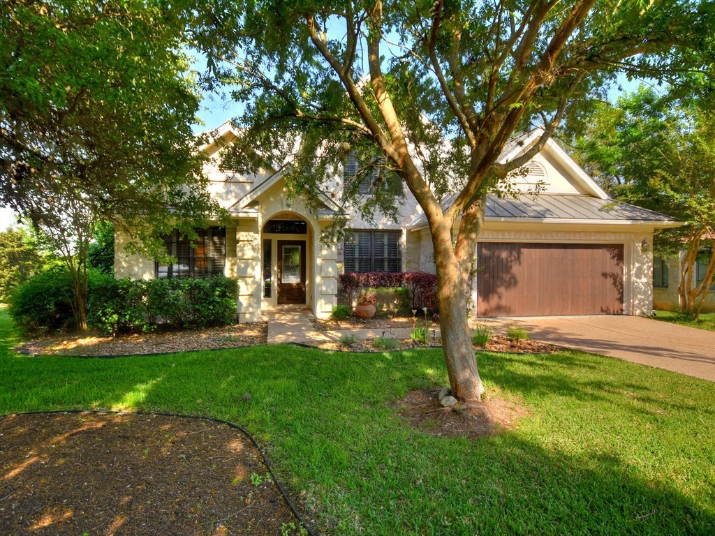 a front view of a house with a garden and trees