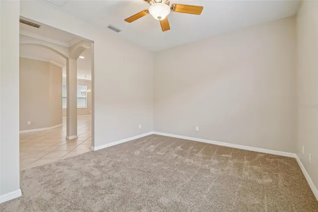 an empty room with closet and a chandelier fan