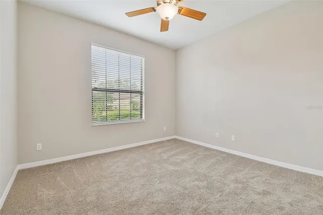 an empty room with a window and a ceiling fan