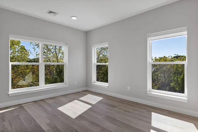 a view of an empty room with wooden floor and a window