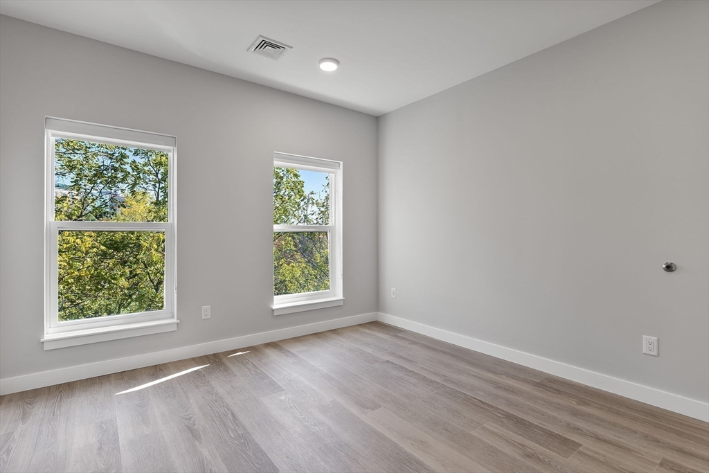 59 Mill Street, Unit 106 Woburn, MA 01801 - Photo 13 of 18 an empty room with wooden floor and windows