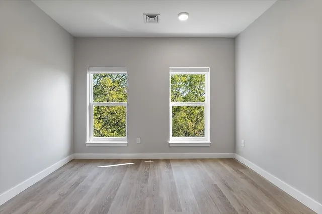 an empty room with wooden floor and windows
