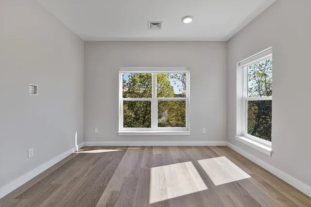 an empty room with wooden floor and windows