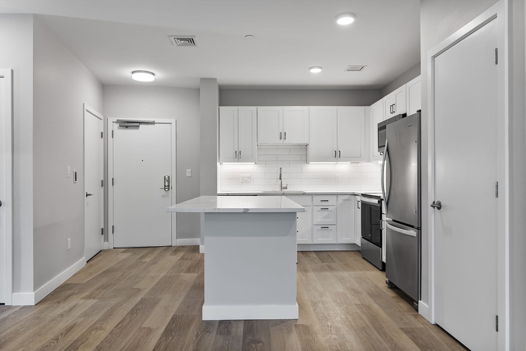 59 Mill Street, Unit 106 Woburn, MA 01801 - Photo 4 of 18 a kitchen with white cabinets and stainless steel appliances