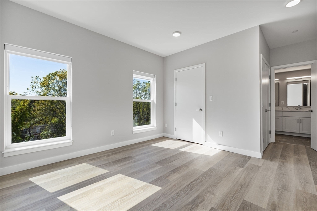 59 Mill Street, Unit 106 Woburn, MA 01801 - Photo 8 of 18 an empty room with wooden floor and windows