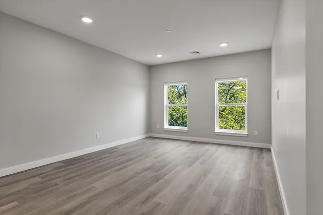 an empty room with wooden floor and windows