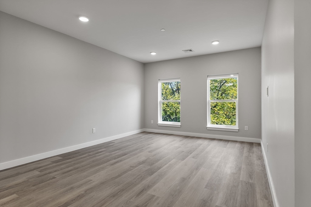 59 Mill Street, Unit 106 Woburn, MA 01801 - Photo 10 of 18 an empty room with wooden floor and windows