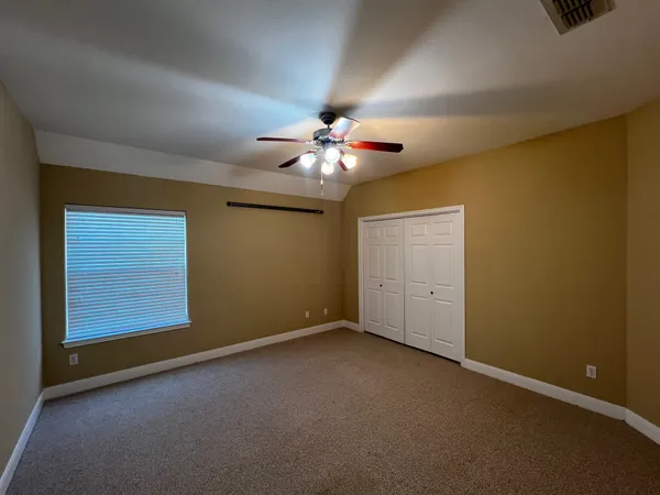 an empty room with windows and chandelier fan