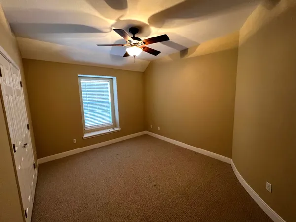 an empty room with a chandelier fan and a window