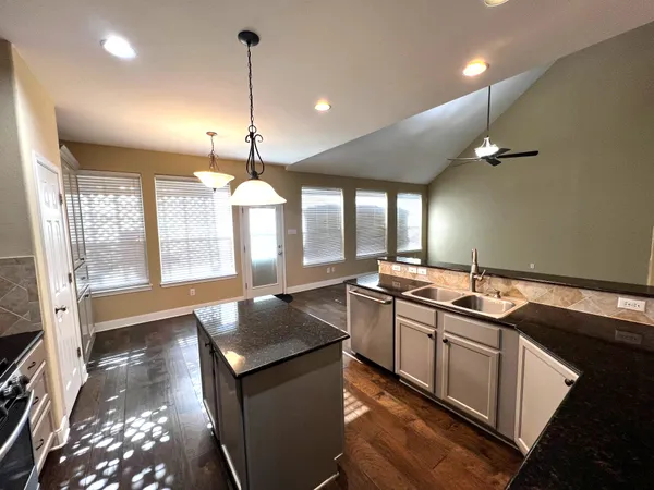 a kitchen with granite countertop sink stove and cabinets