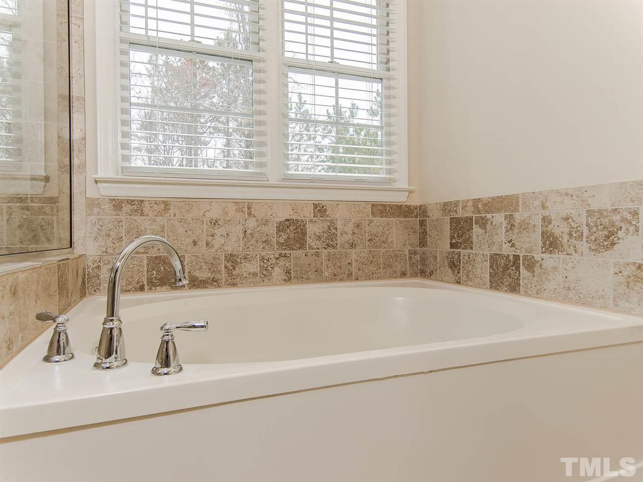 5424 Stewartby Drive Raleigh, NC 27613 - Photo 16 of 25 a bathroom with bathtub a window and a sink