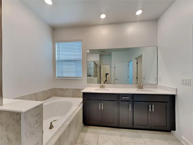 a bathroom with a granite countertop bathtub sink double and mirror