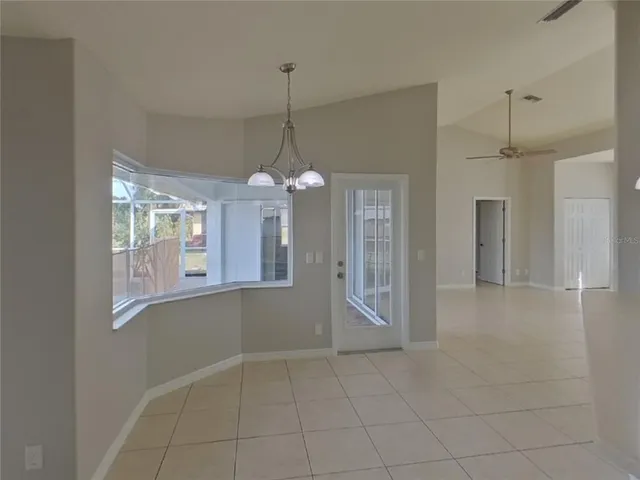 a view of an empty room with window and chandelier