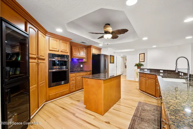a kitchen with stainless steel appliances kitchen island granite countertop a refrigerator a stove top oven a sink and dishwasher