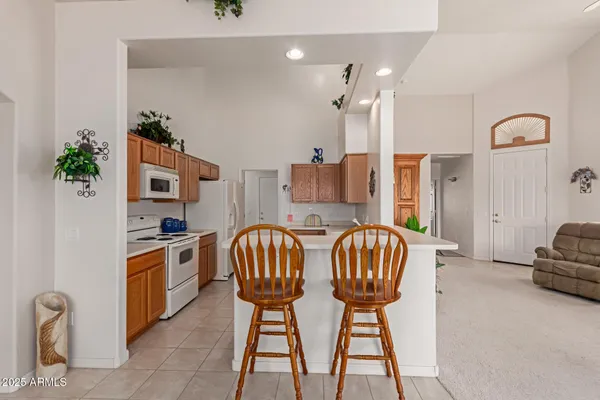 a kitchen with stainless steel appliances granite countertop a sink a stove a refrigerator a dining table and chairs