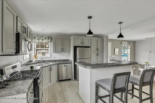 a kitchen with stainless steel appliances granite countertop a sink a stove a dining table and chairs