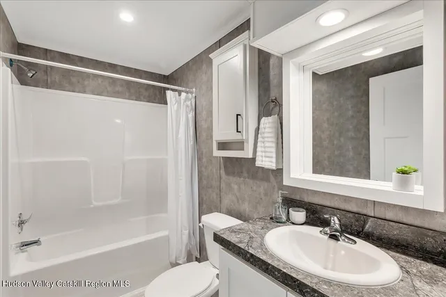 a bathroom with a granite countertop sink toilet a mirror and shower