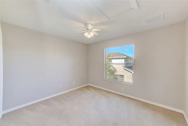 an empty room with a window and ceiling fan