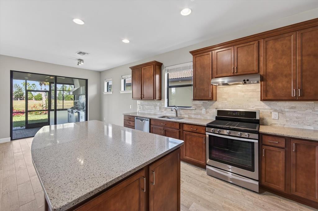 6745 Chester Trail Bradenton, FL 34202 - Photo 27 of 95 a kitchen with kitchen island granite countertop wooden cabinets a stove and a sink