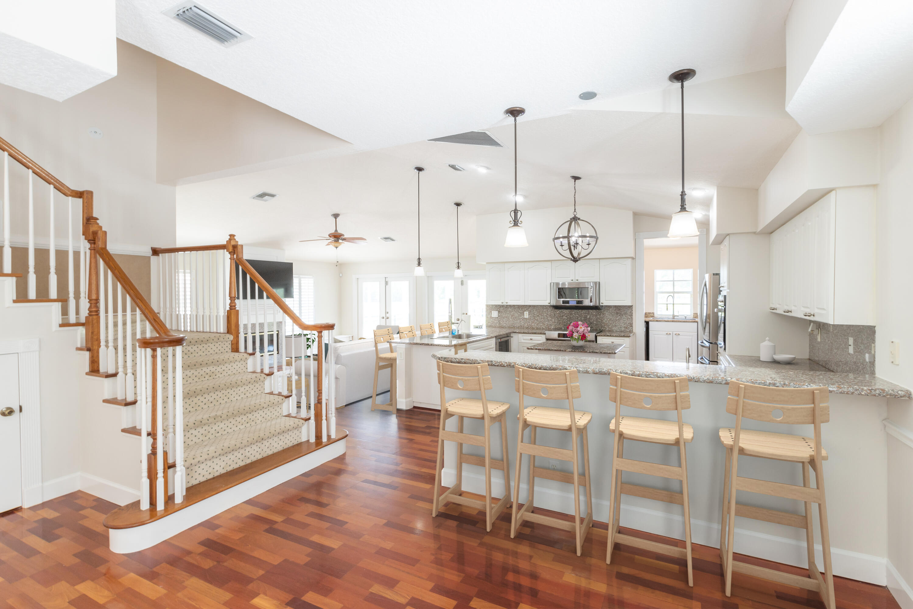 13230 Running Water Road Palm Beach Gardens, FL 33418 - Photo 4 of 32 a kitchen with stainless steel appliances kitchen island granite countertop a table chairs in it and wooden floors