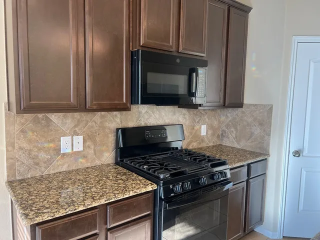 a kitchen with stainless steel appliances granite countertop a sink stove and refrigerator
