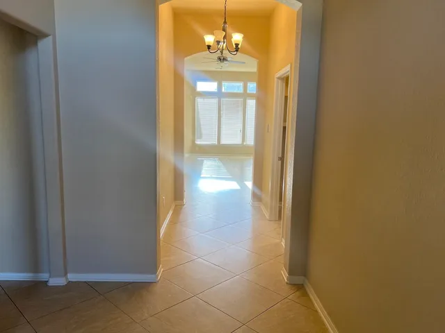 a view of a hallway with chandelier and a dining room