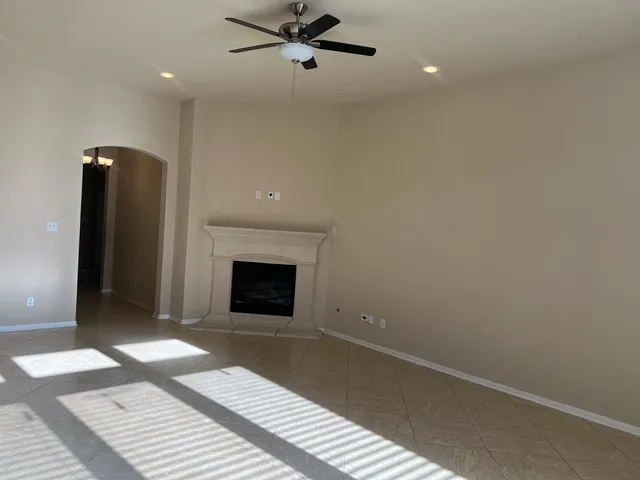 an empty room with fireplace and a chandelier fan