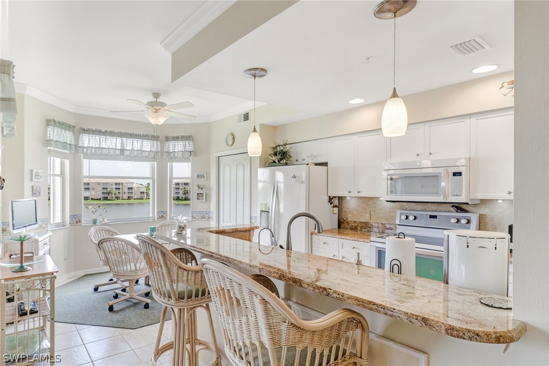 14101 Brant Point Circle, Unit 3303 Fort Myers, FL 33919 - Photo 3 of 30 a large kitchen with kitchen island a large counter space a sink appliances and a dining table view
