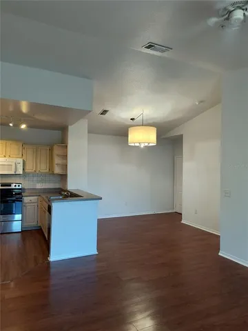 a view of a kitchen with a sink and dishwasher a stove top oven with wooden floor