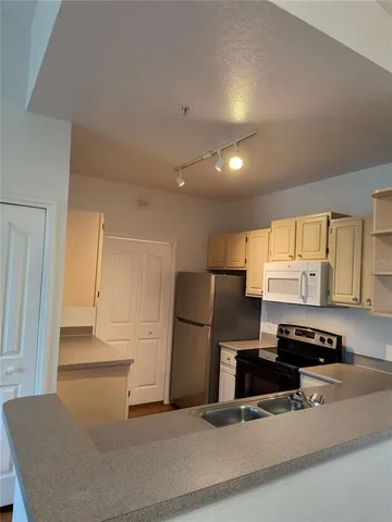 a kitchen with a refrigerator a stove and a sink with wooden floor
