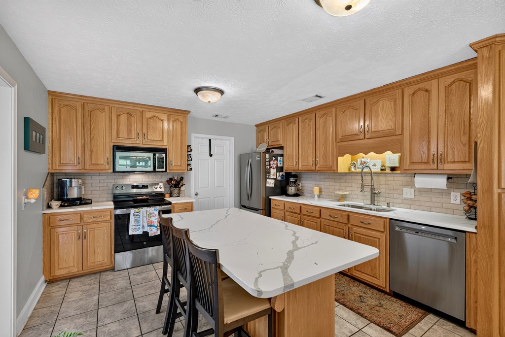 481-494 Sand Pit Road Mauk, GA 31058 - Photo 15 of 94 a kitchen with stainless steel appliances a stove top oven a sink dishwasher and a refrigerator with wooden cabinets