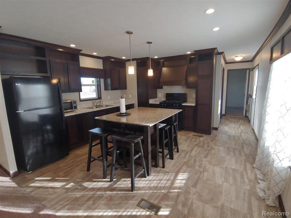 121 Haskin Street Boon, MI 49618 - Photo 3 of 13 Kitchen featuring black appliances, ventilation hood, and dark wood finish cabinets