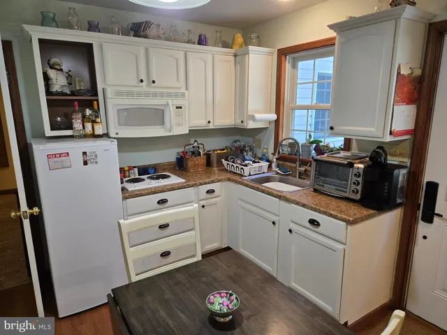 a kitchen with granite countertop white cabinets and white appliances