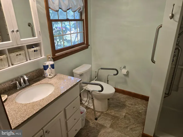 a bathroom with a granite countertop sink toilet and a mirror