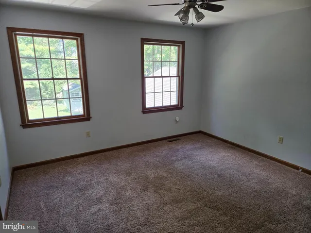 an empty room with a window and a ceiling fan