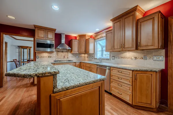 a kitchen with stainless steel appliances granite countertop wooden floors a stove and a sink