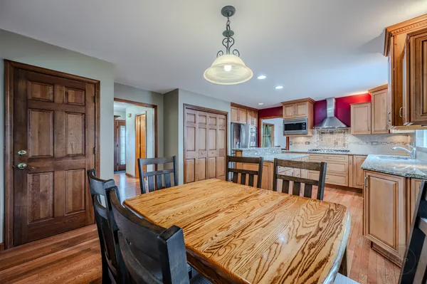 a dining room with stainless steel appliances granite countertop a table chairs and a chandelier