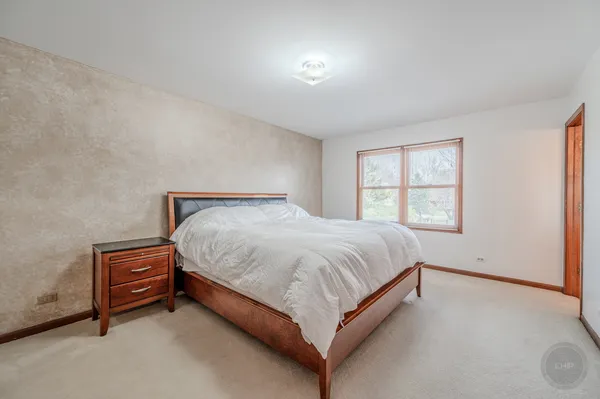 a spacious bedroom with a bed and a dresser with mirror