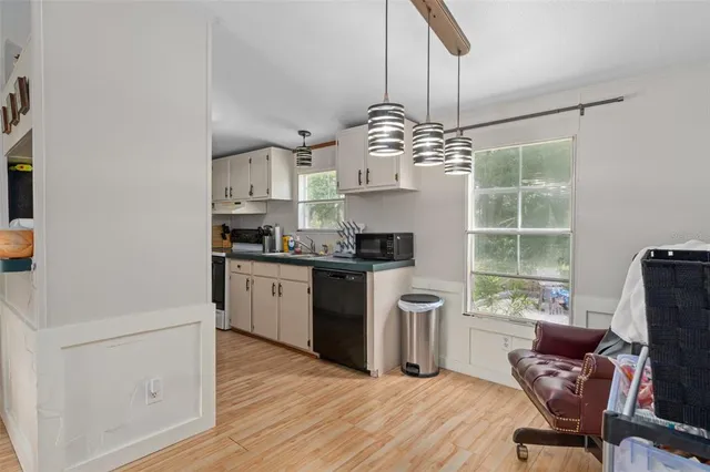 a kitchen with kitchen island stainless steel appliances a dining table chairs and wooden floor